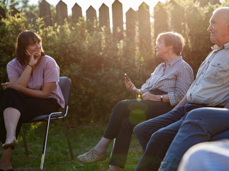 Several persons of The New Patrons of Wietstock are sitting in the evening sun and talking to each other