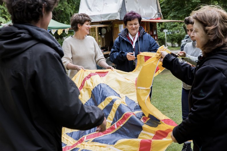 Several persons of The New Patrons of Steinhöfel hold a large banner in their hands.