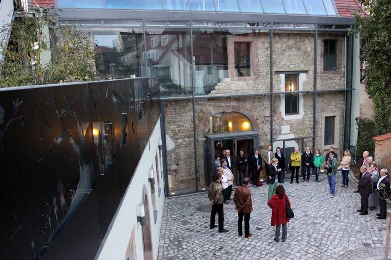 People and members of The New Patrons move around in the courtyard of the Architektur- und Umwelthaus at the inauguration