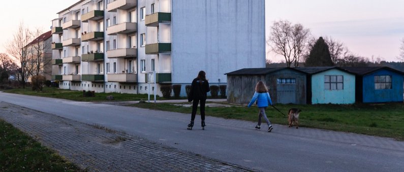 Personen auf einer Straße vor einem Wohnblock in Züsedom