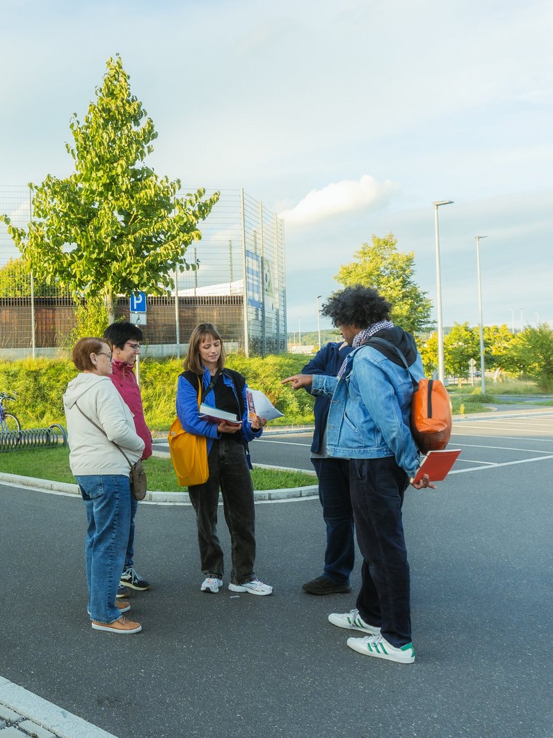 Three people are standing on a village street and talking.