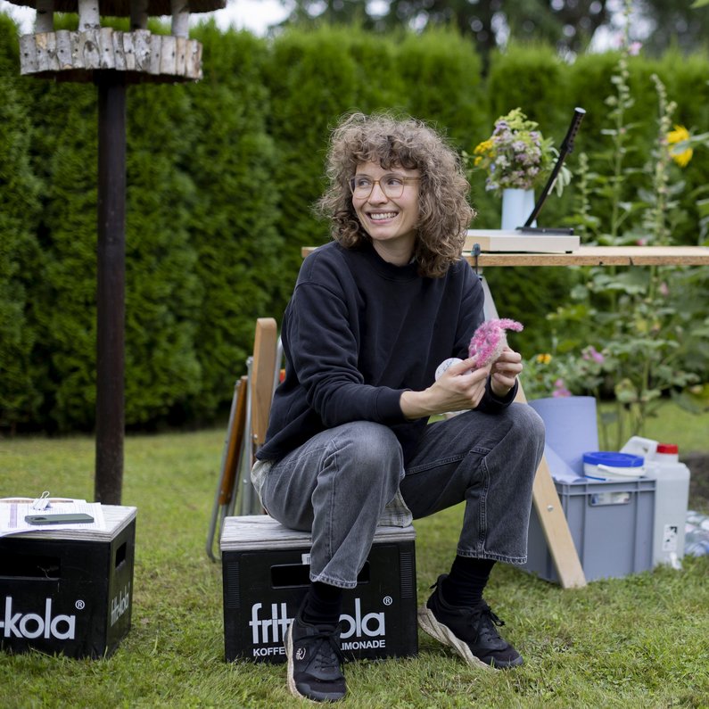 The New Patrons of Wietstock A person is sitting on a box in the garden and laughing.
