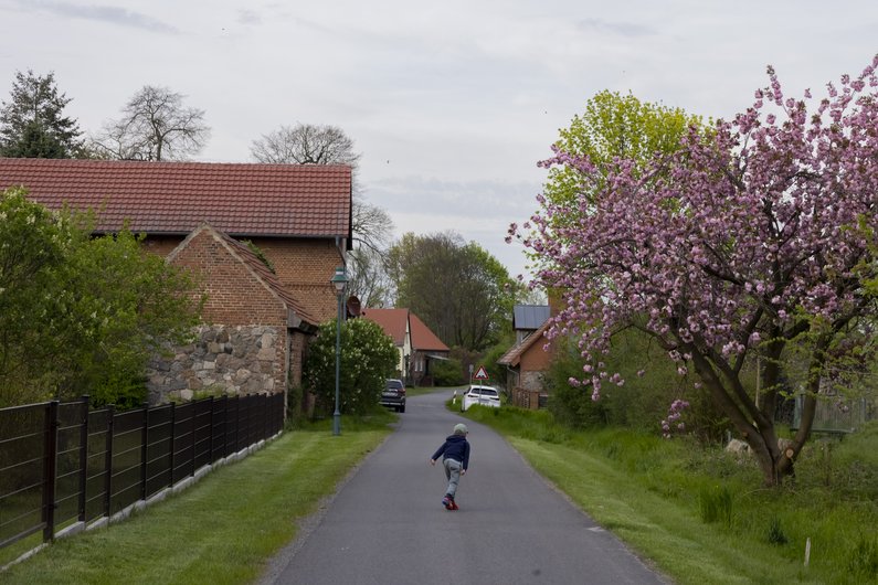 A child runs on a road surrounded by trees in Sauen