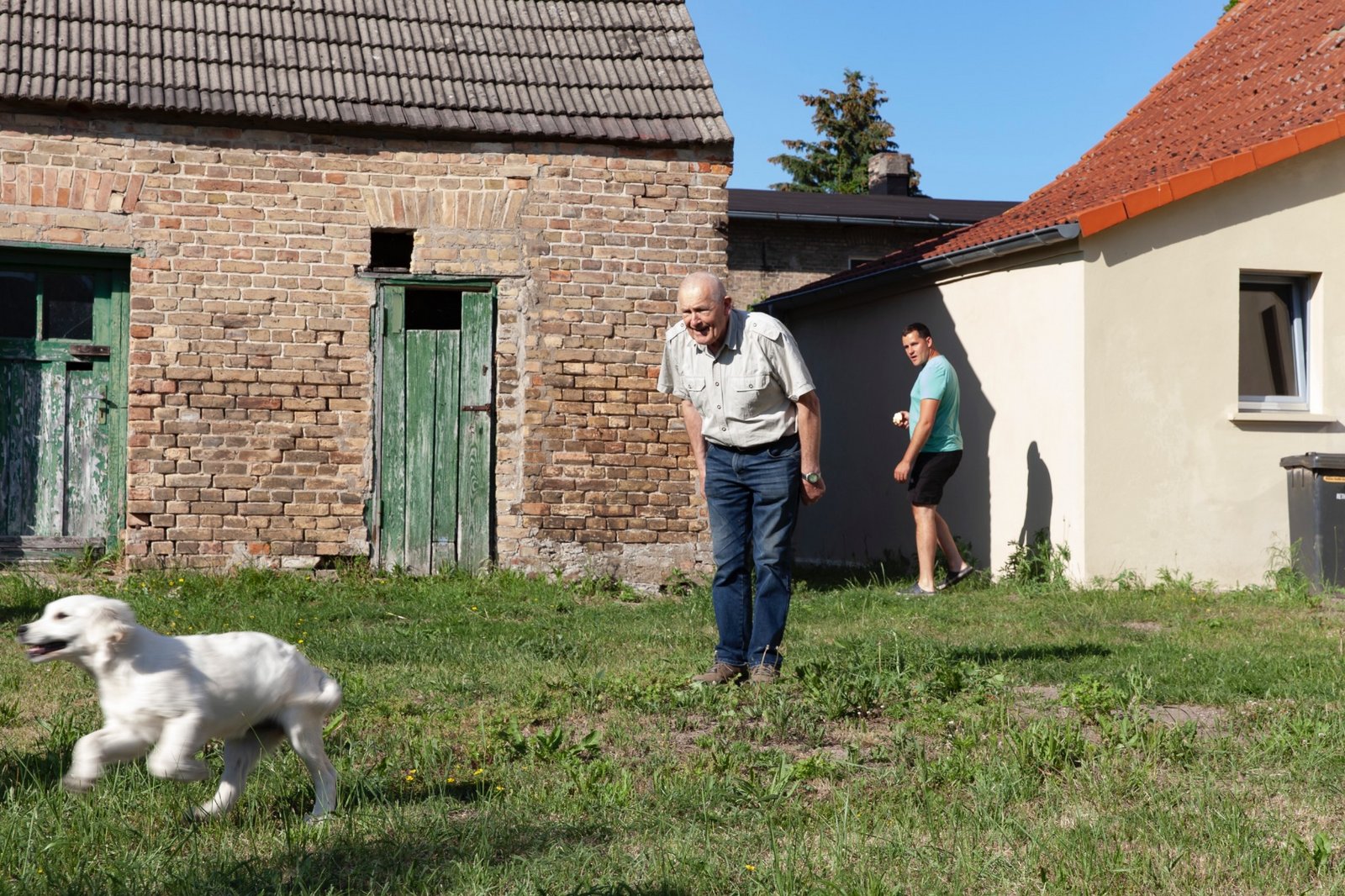 Eine Person der Neuen Auftraggeber von Wietstock steht mit einem Hund in einem Garten