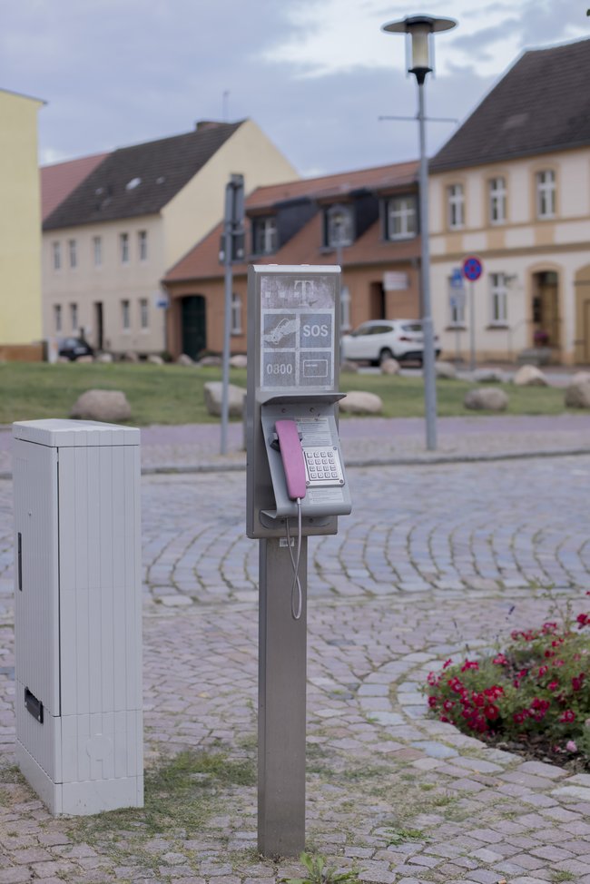 Ortsansicht Penkun Altes öffentliches Telefon mit SOS-Zeichen steht in menschenleerem dörflichem Umfeld