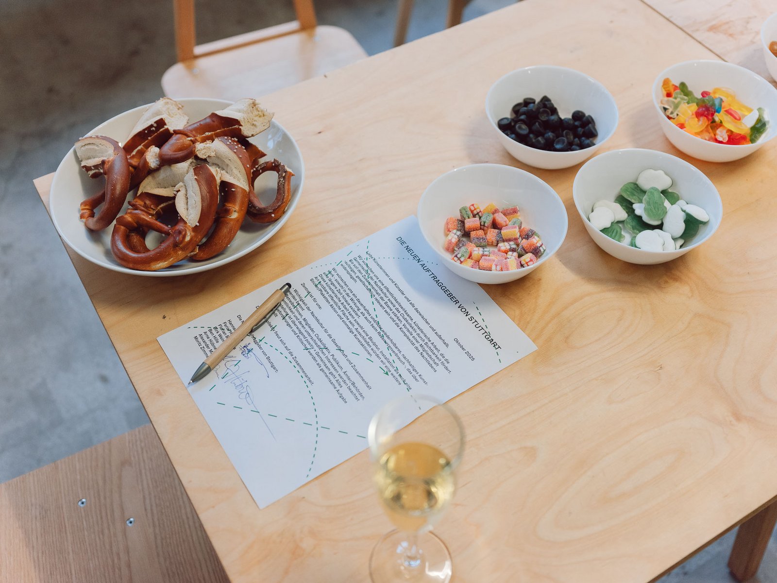 Ein Vertrag mit Stift liegt auf einem Tisch, daneben kleine Schälchen mit Snacks und ein Getränk