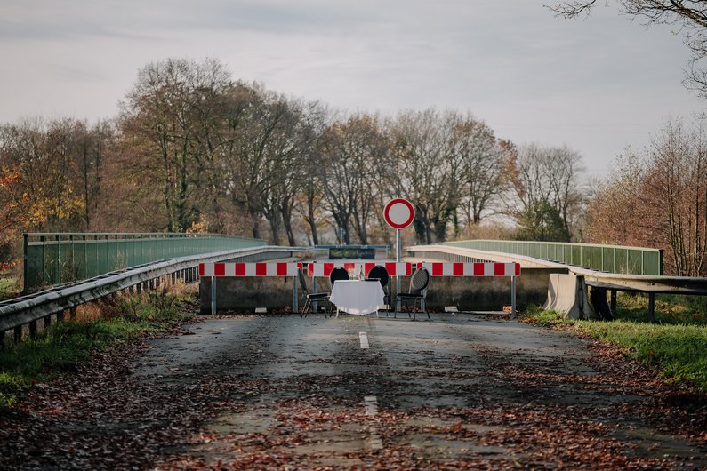 Tisch mit Tischdecke im freien auf einer abgesperrten Brücke