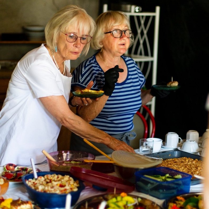 Several people from the New Patrons of Steinhöfel stand at a richly laid buffet of dishes