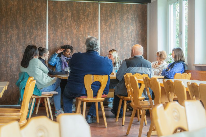 Several people are sitting around a table in a room.