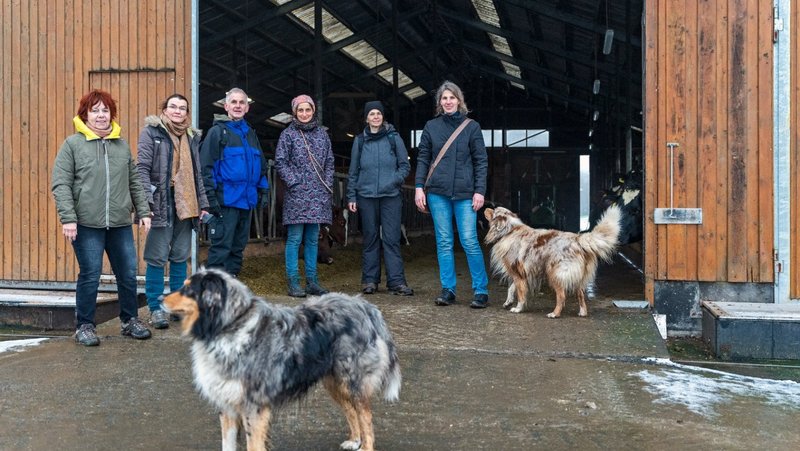 Group of The New Patrons of Waldeck-Frankenberg and two dogs stand at the entrance gate of a farm building.