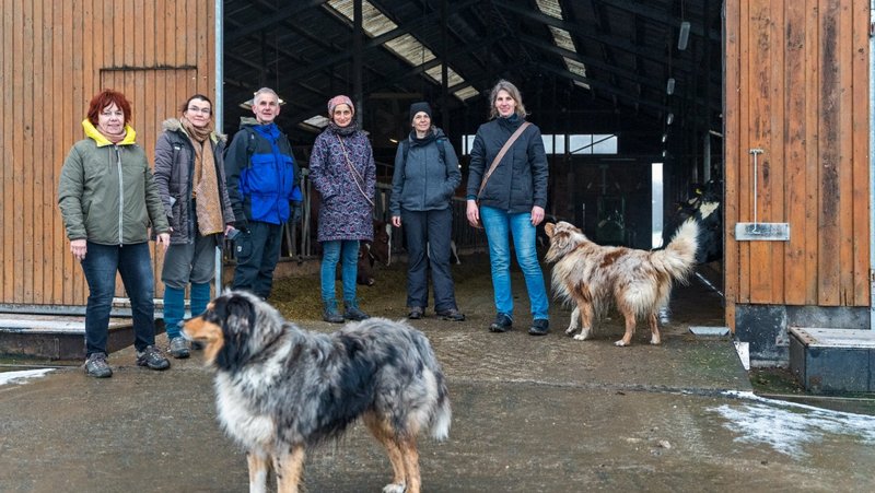 Gruppe der Neuen Auftraggeber von Waldeck-Frankenberg und zwei Hunde stehen am Eingangstor von einem landwirtschaftlichen Gebäude