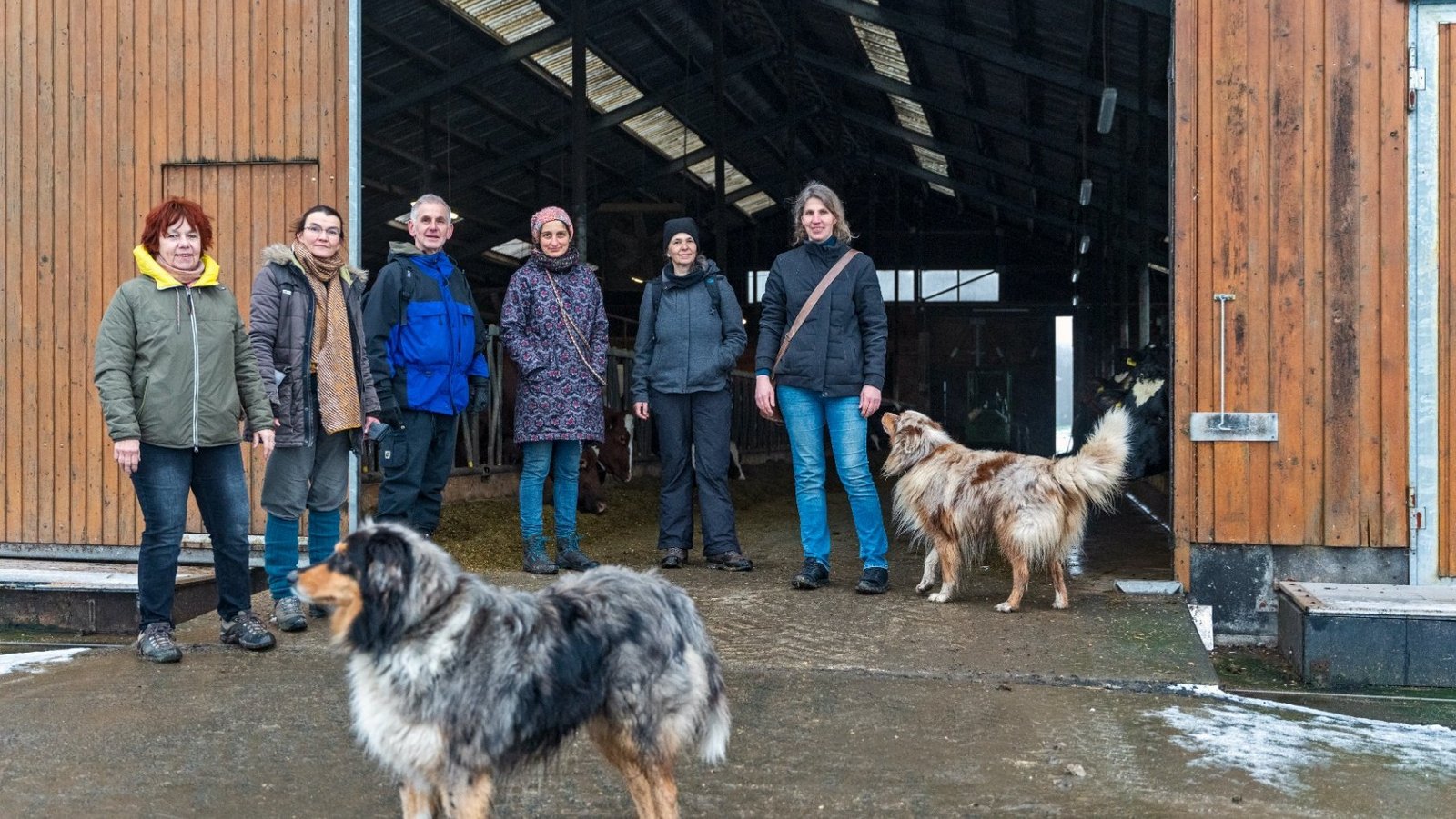 Gruppe der Neuen Auftraggeber von Waldeck-Frankenberg und zwei Hunde stehen am Eingangstor von einem landwirtschaftlichen Gebäude