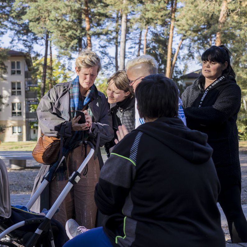 Auftraggebergruppe mit Kinderwagen von Eberswalde stehen vor einem Wohngebäude und besprechen sich.