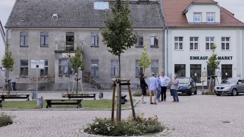 Personen der Neuen Auftraggeber, Häuser und Baum auf dem Marktpatz von Penkun