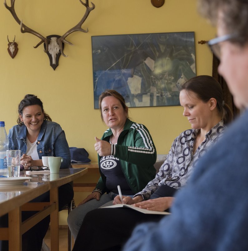 New Patrons of Sauen sit at a table with mediator Lea Schleiffenbaum and artist Judith Hopf