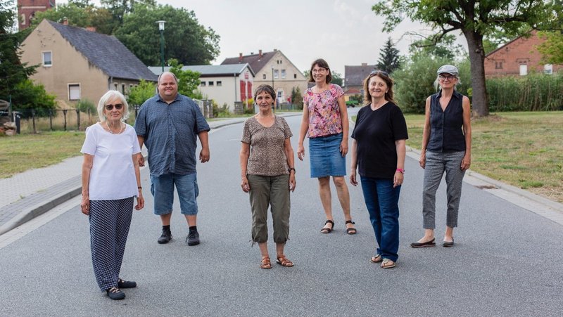 Gruppe der Neuen Auftraggeber von Steinhöfel stehen im Dorf 