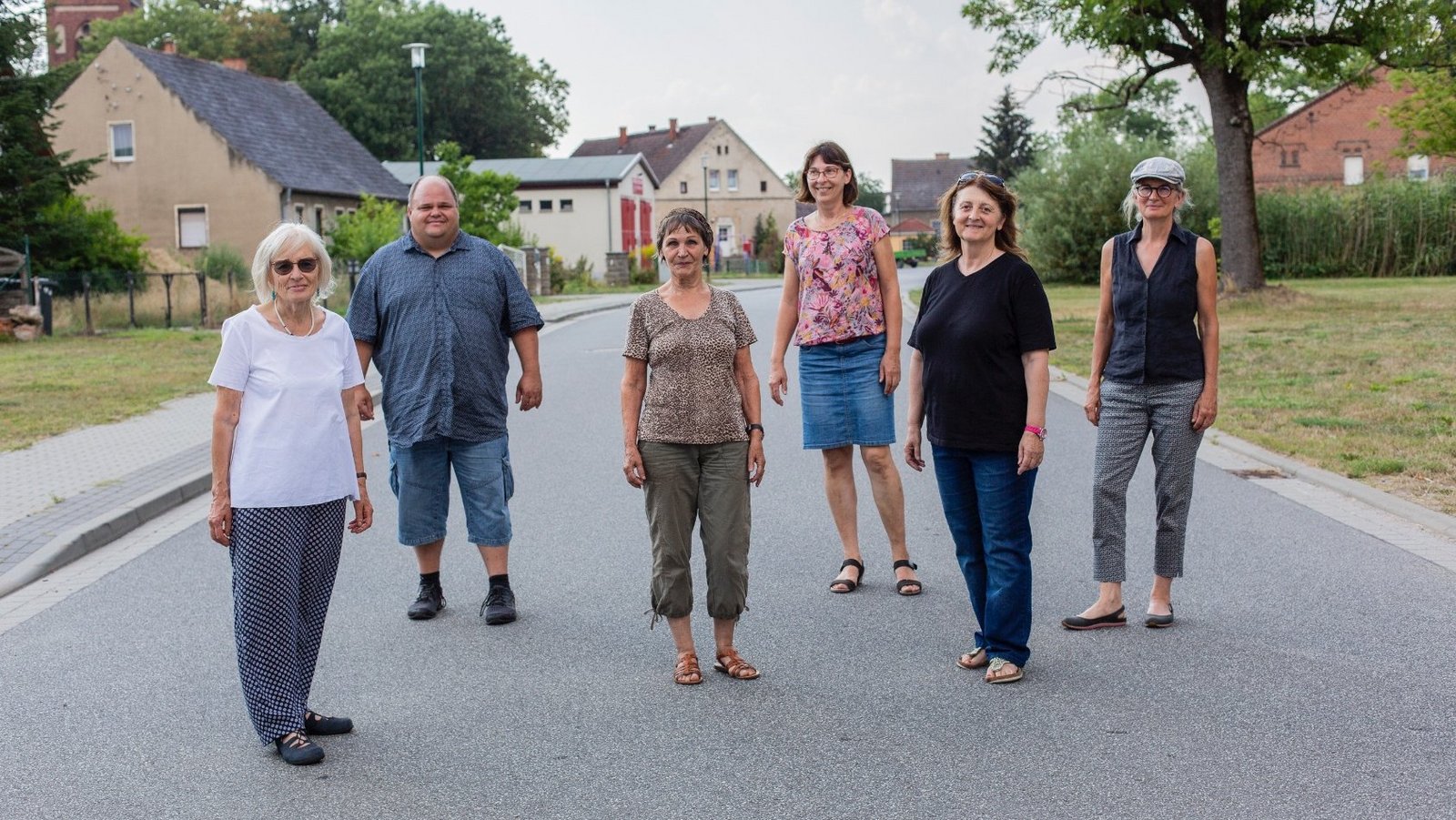 Gruppe der Neuen Auftraggeber von Steinhöfel stehen im Dorf 