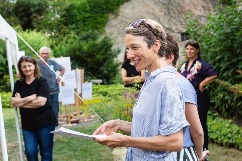 Mediatorin Lena Ziese steht im Garten mit mehreren Personen der Neuen Auftraggeber von Steinhöfel