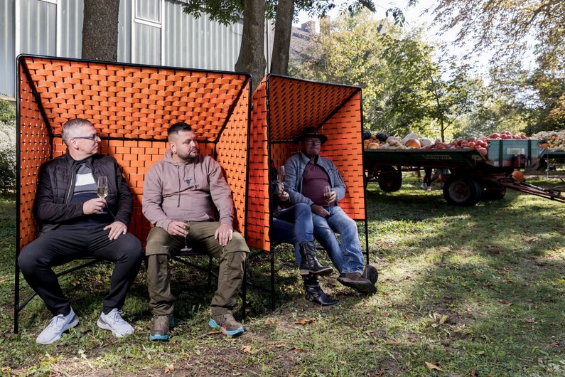 Members The New Patrons sitting in the prototypes of the orange Züsedom-Bank