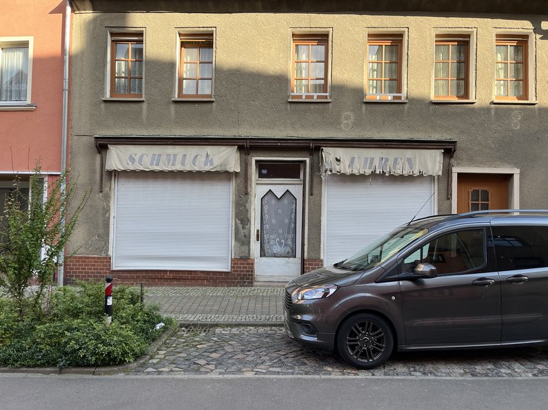 Parkendes Auto vor einem Haus mit heruntergelassenen Rolläden vor den Fenstern