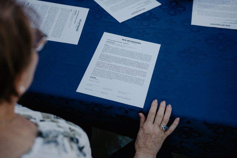 The New Patrons of Amberg – Am Bergsteig The commission to be signed is on the table in front of a person.