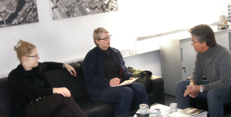 Three members of The New Patrons of Dortmund are sitting on a sofa and discussing