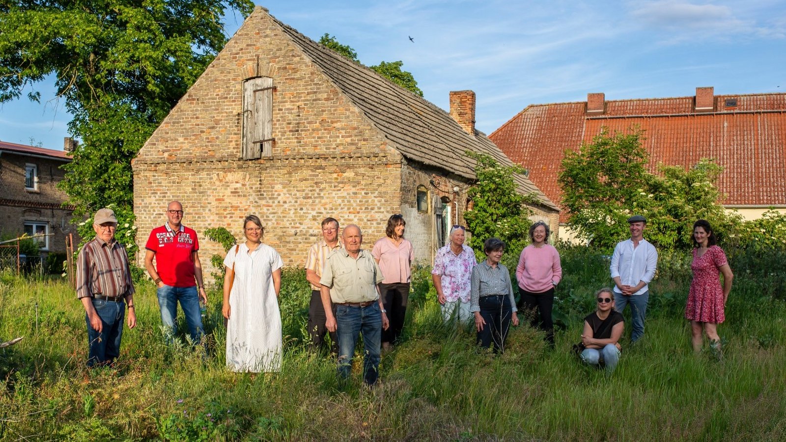 Group photo of The New Patrons of Wietstock in front of an old building in the village