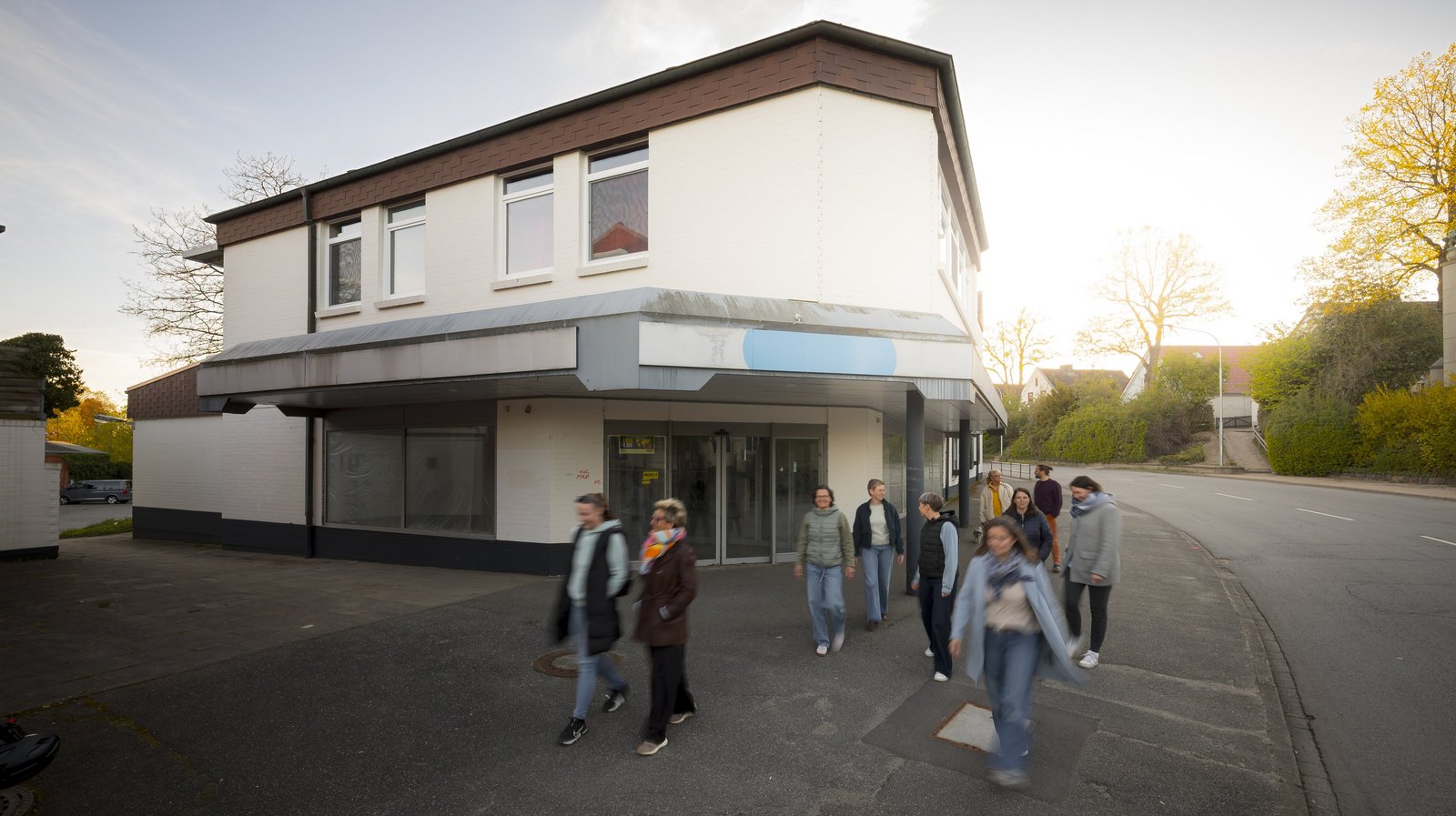 Eine Gruppe von Menschen an einer menschenleeren Straßenecke mit einem leeren Geschäftsgebäude
