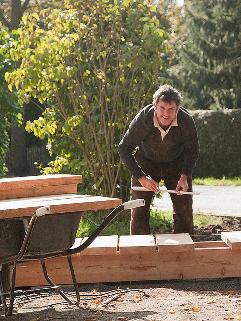 A member of the landscape architecture studio LE BALTO is in the process of measuring wooden planks for the wooden footbridge " Pleasure Walk" in Kleinliebenau