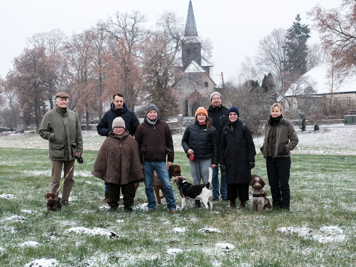 Gruppenfoto der Auftraggebergruppe von Sauen mit Ateliers Pompiers, Judith Hopf und Florian Zeyfang und Mediatorin Lea Schleiffenbaum auf einer Wiese im Winter