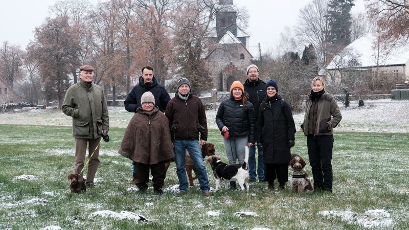 Gruppenfoto der Auftraggebergruppe von Sauen mit Ateliers Pompiers, Judith Hopf und Florian Zeyfang und Mediatorin Lea Schleiffenbaum auf einer Wiese im Winter