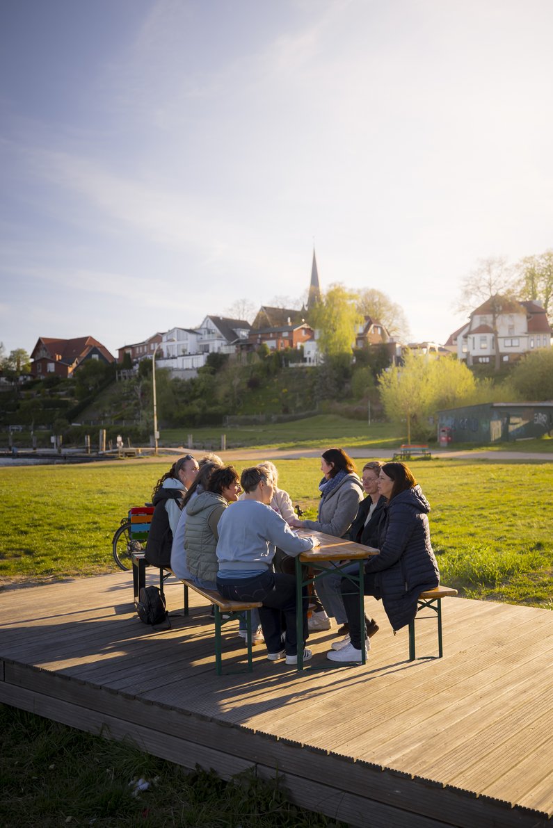 Eine Gruppe sitzt draußen in der Abendsonne an einem Tisch.