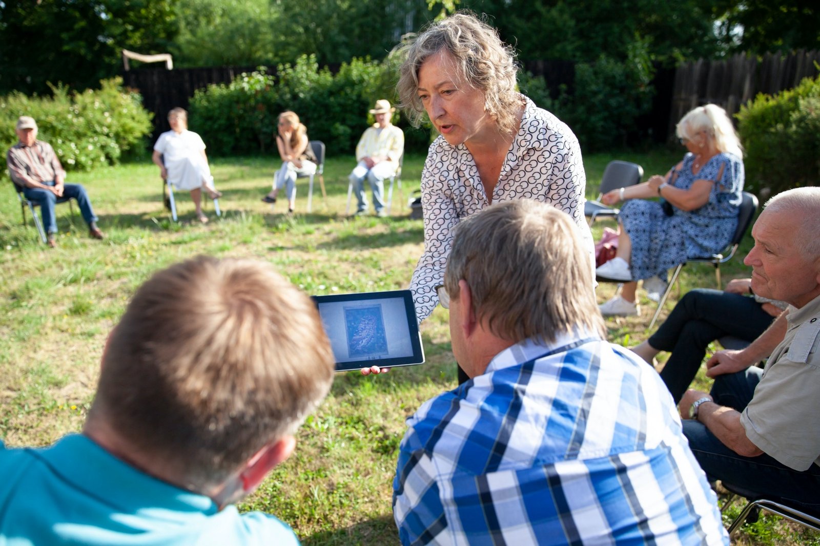 Mediatorin Susanne Burmester beim Ortstermin in Wietstock Mediatorin Susanne Burmester hält ein Ipad und zeigt es zwei Personen der Neuen Auftraggeber von Wietstock