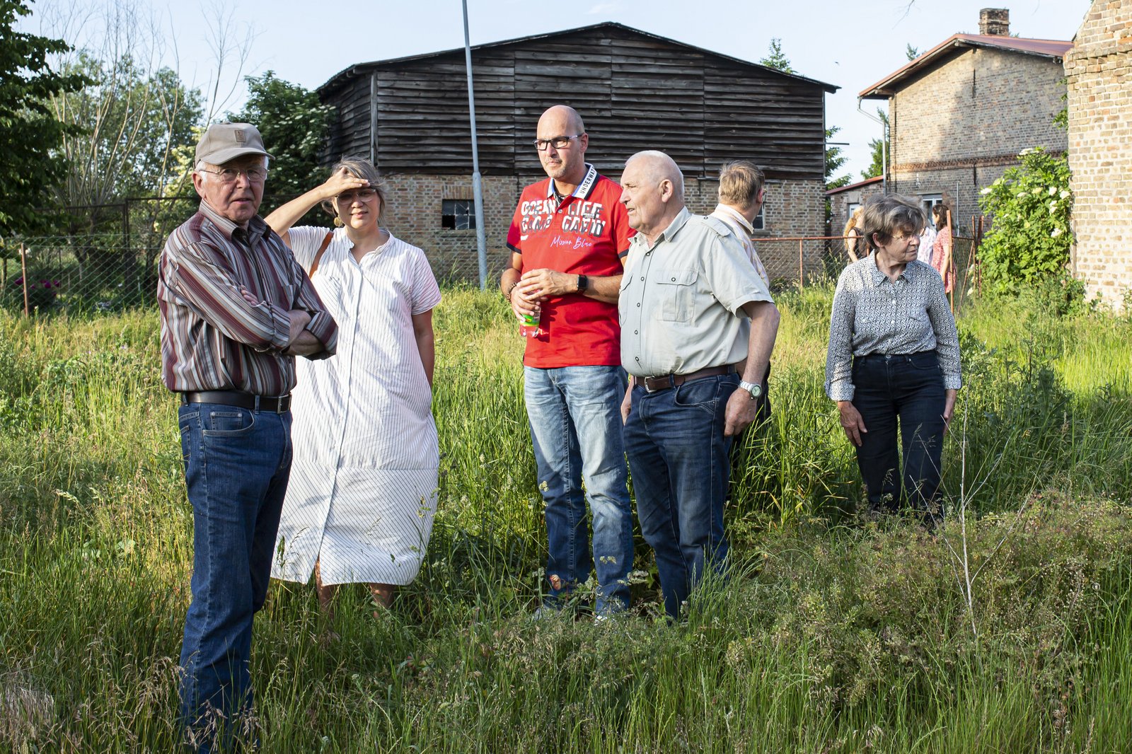 Auftraggebergruppe von Wietstock steht mit Künstlerin Antje Majewski vor einem Haus. 