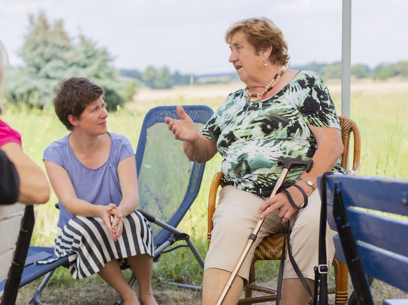 Mediator Sophia Trollmann sits on a bench and talks to Chairwoman of the Seniors' Advisory Council Renate Kliems in Steinhöfel.