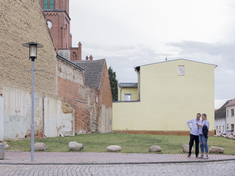 Künstlerin Lena Henke mit Auftraggeber auf der Straße mit Häusern