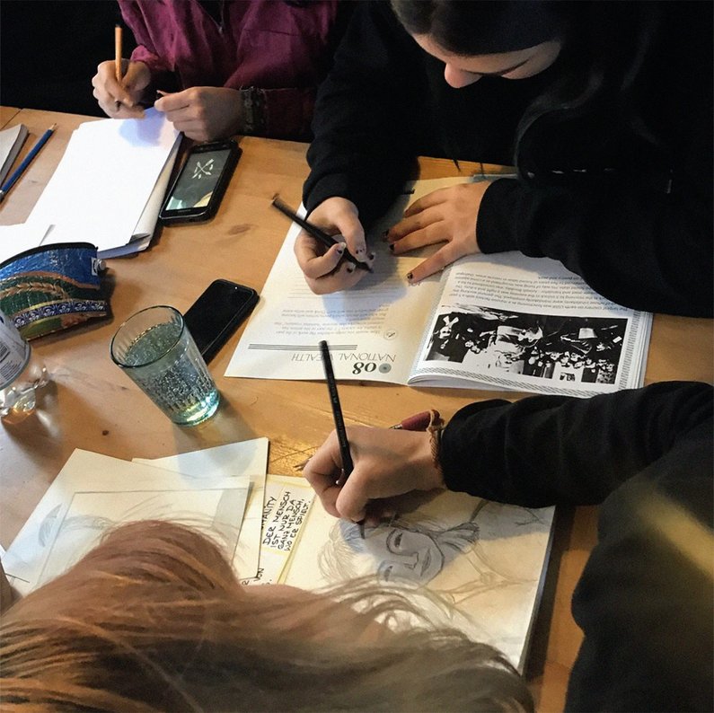 Sicht auf Kinder von oben, die mit Stiften in den Publikationen von "Anthropology for Kids" zeichnen und schreiben