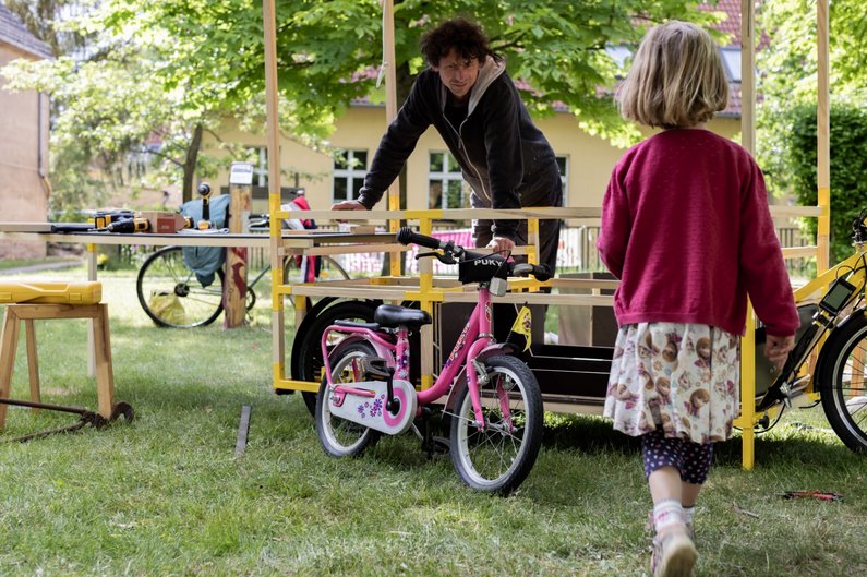 Ein Bewohner und ein Kind bereiten beim Bauworkshop Steinhöfel einen Stand vor