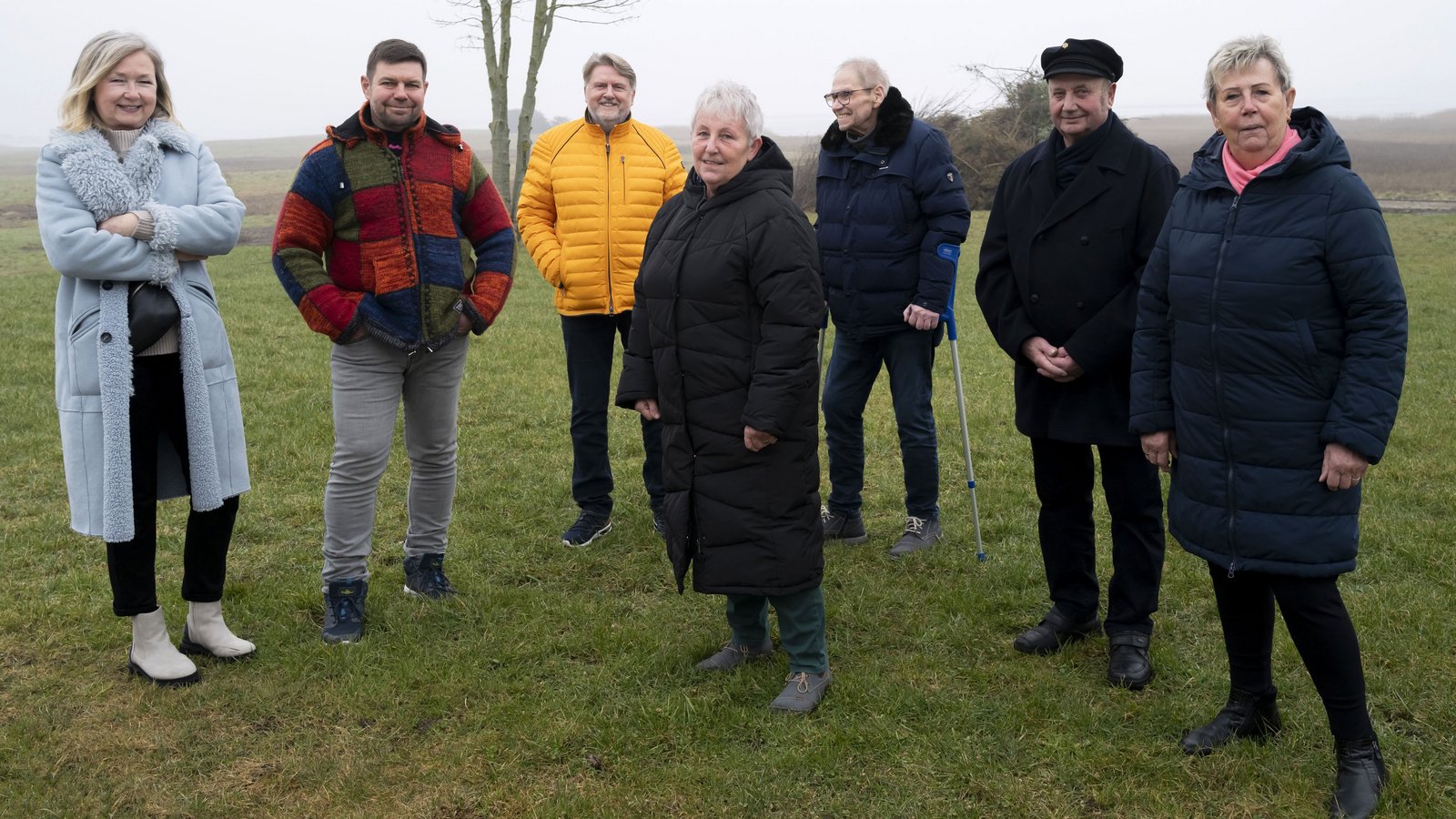 A group of people stands together in a field for a photo.