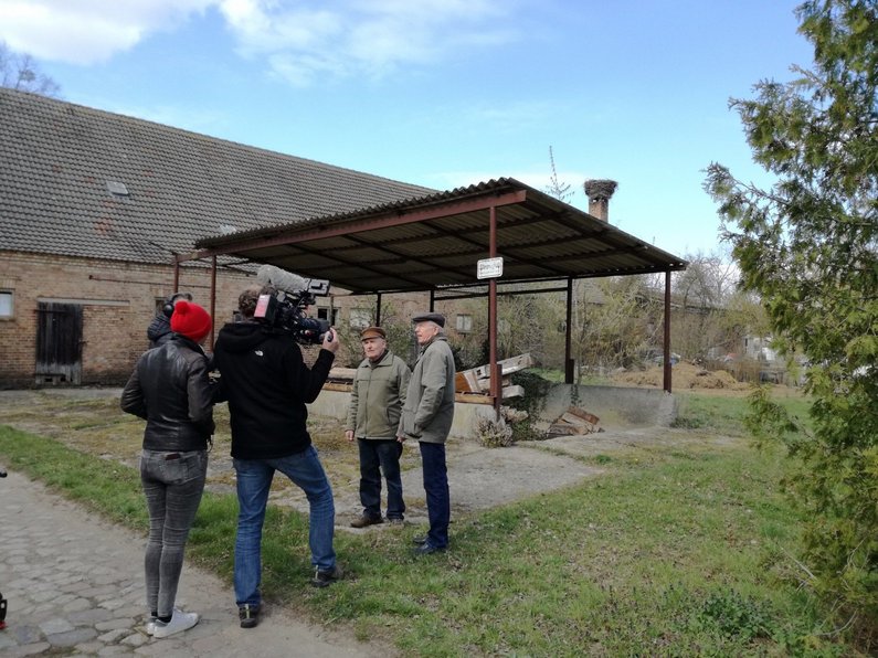 Members of The New Patrons of Wietstock stand with television reporters at the site of the future community garden.