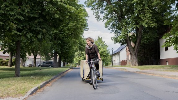 A member of The New Patrons is cycling around the village