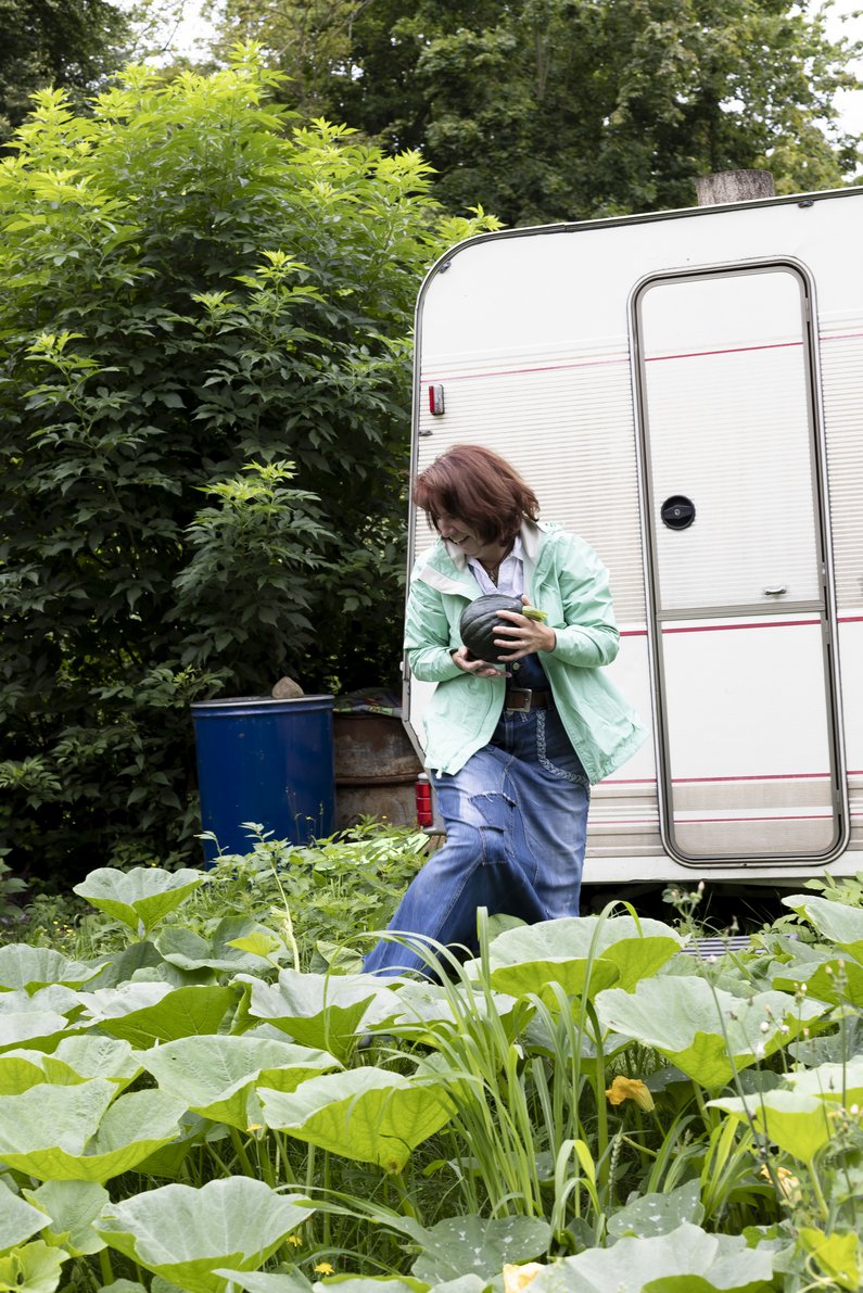 A person is standing in front of a caravan in the garden.